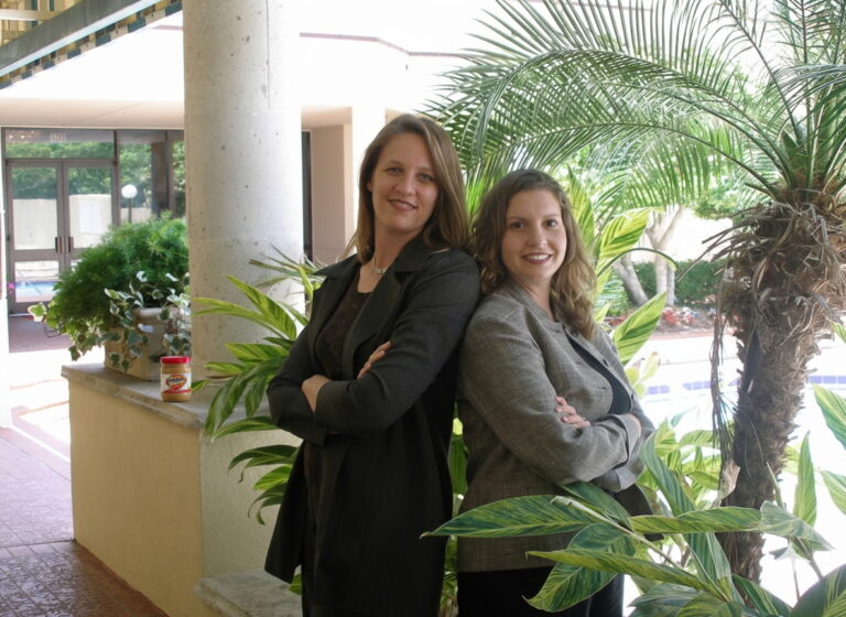 Diane Elkins and Desiree Pinder pose together with a jar of peanut butter on the ledge behind them.