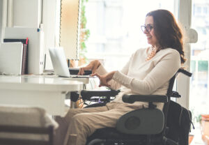 Side view of a woman with physical disability working on a laptop in the office.