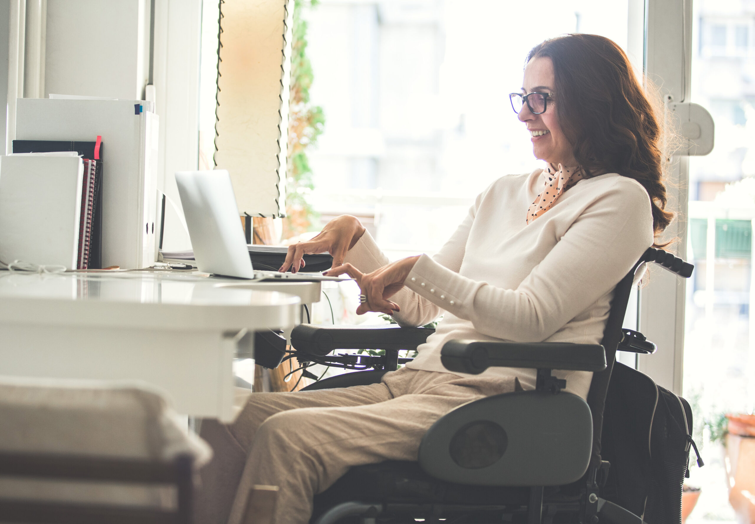 Side view of a woman with physical disability working on a laptop in the office.
