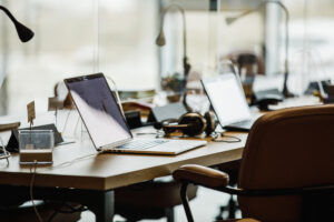 Selective focus shot of minimalist desk with laptops and headphones in a co-working office space. Part of a series.