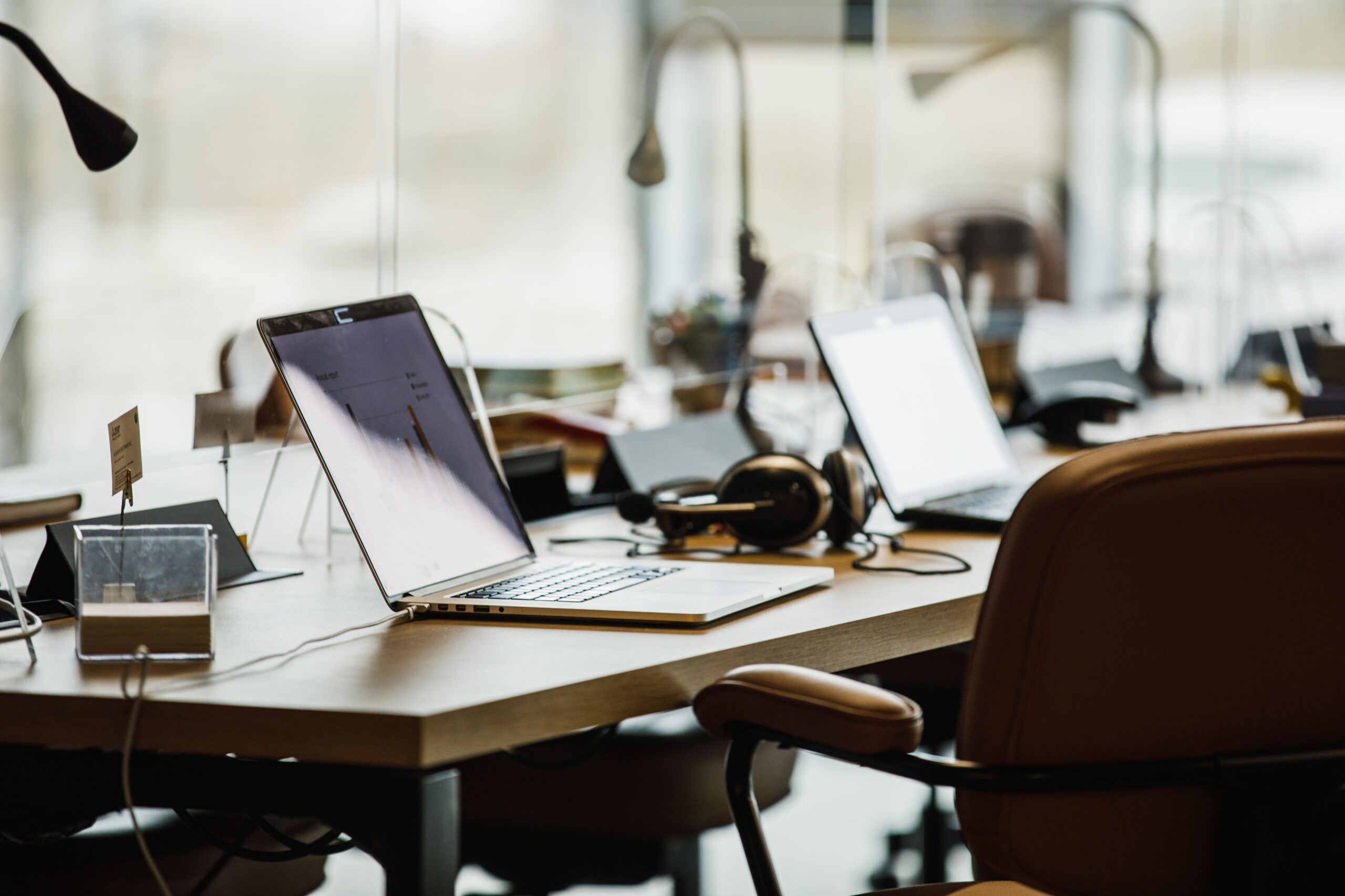 Selective focus shot of minimalist desk with laptops and headphones in a co-working office space. Part of a series.