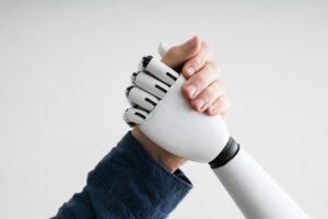 A human hand is shown arm wrestling or shaking hands with a robot hand.